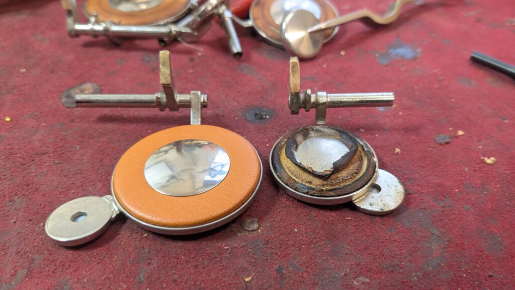 A photo showing two saxophone keys one with a brand new pad and the other with a pad that has torn.